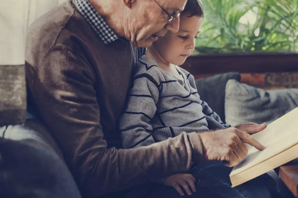 Old man reading books to his grand child